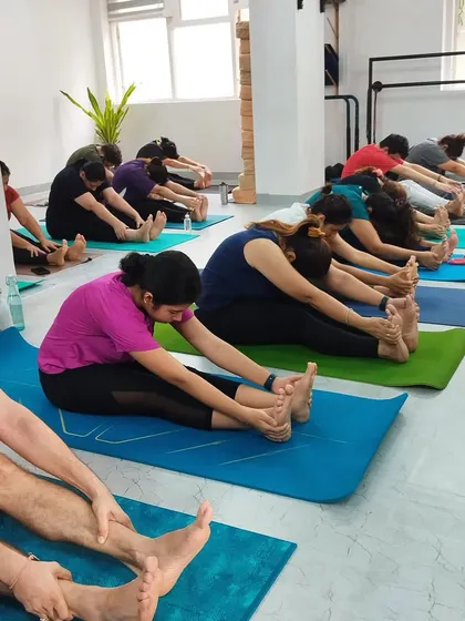 Another angle of a deep stretch in a group setting. It reinforces the ample space available for each person to practice without feeling crowded, ensuring a quality experience for your clients.