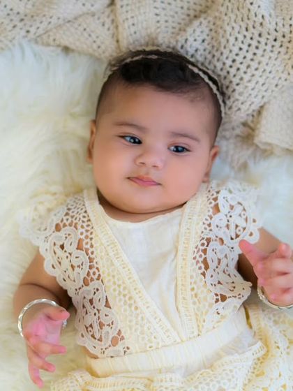 A beautiful overhead shot of a baby girl in a lace outfit. The neutral tones and soft textures create a timeless and artistic portrait.