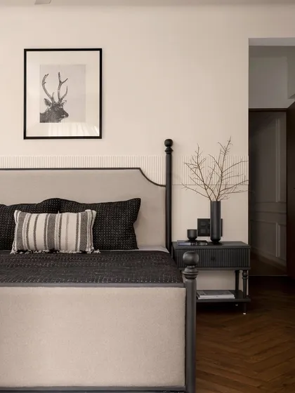 Another angle of the master bedroom, showing the relationship between the bed, the bedside table, and the doorway. The herringbone flooring adds warmth and texture to the space.