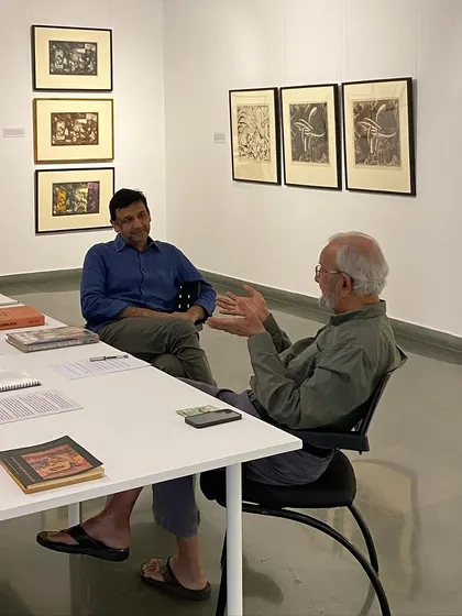 The artist and Mr. Poddar discussing the works at the library table.