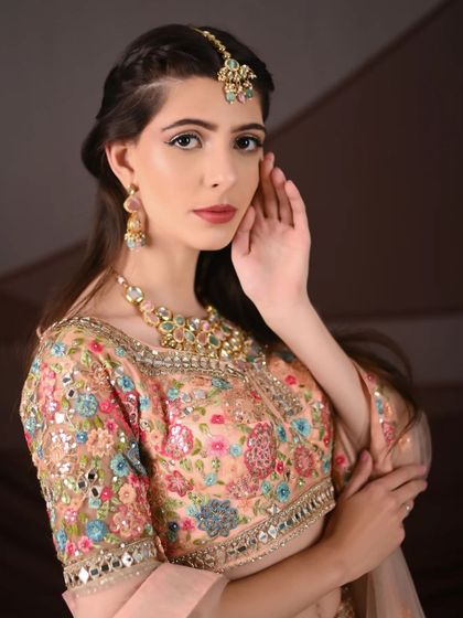 A close-up on the details. This shot focuses on the beautiful floral embroidery of the blouse and the elegant jewellery paired with it, all available for rent.