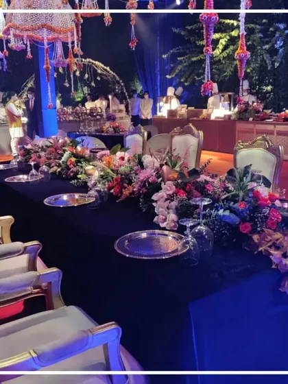 An elegant sit-down dinner arrangement for an evening celebration. The table is set with a dark velvet cloth, premium silver plates, and a lush floral centerpiece, demonstrating our attention to detail in tablescaping.