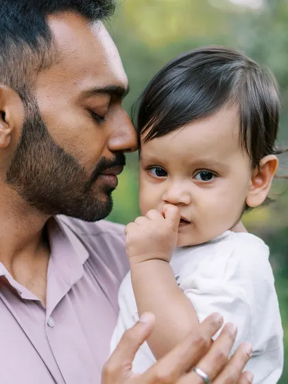 A father and son share a quiet, tender moment. The baby's direct look at the camera is captivating.