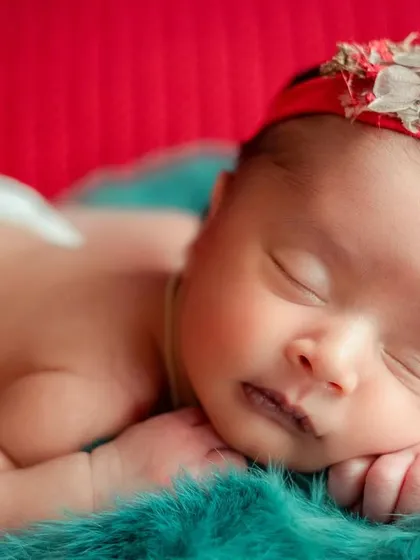 A pop of color can make a simple portrait stand out. This baby is posed on a vibrant red and teal background, highlighting their beautiful skin tone.