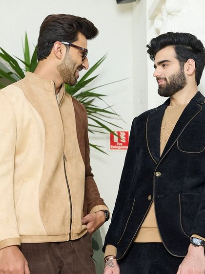 Two models in conversation, wearing the beige suede and navy velvet jackets. This image captures the social aspect of style and the confidence my clothes inspire.