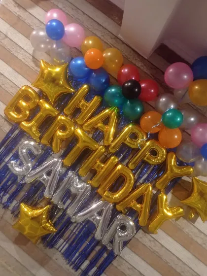 A simple wall decoration using gold and silver "Happy Birthday" foil balloons, surrounded by a few colorful latex balloons.