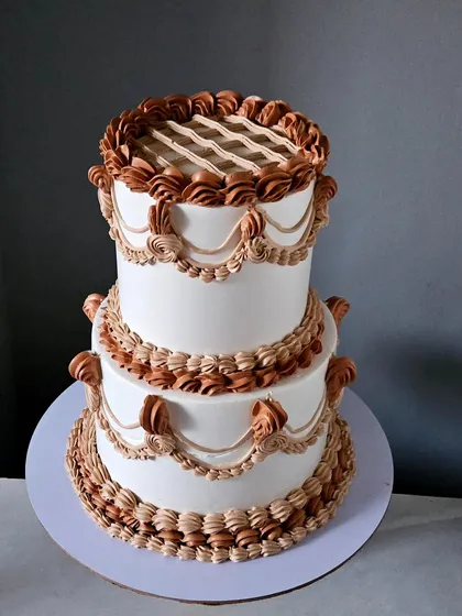 I have a deep appreciation for classic techniques. This two-tiered cake showcases my vintage piping skills, with intricate shell borders, swags, and lattice work, all piped by hand in beautiful boho shades of cream.