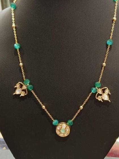 A simple gold chain necklace with Kundan charms and green beads. It's lightweight and stylish, making it suitable for both work and casual outings.
