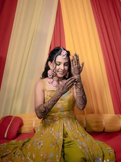 The joy of a Mehendi ceremony captured perfectly. I created a fresh, vibrant makeup look with soft waves in her hair, adorned with floral jewelry to match the festive mood.