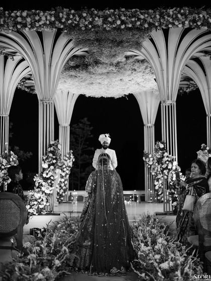 A powerful black and white shot of the bride and groom at the mandap, capturing the grandeur of the decor and the solemnity of the moment.