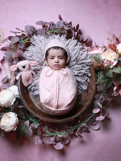Our 'Dry Lagoon' theme in pink, with the baby in a bowl surrounded by a wreath of flowers and leaves against a dusty rose backdrop.