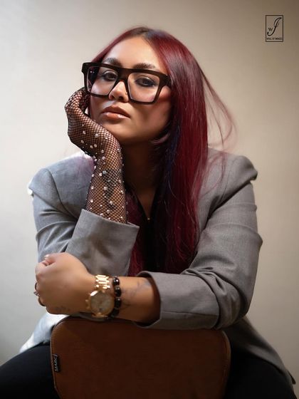 A thoughtful pose that highlights the model's unique style, from her colored hair to the sparkling mesh glove.