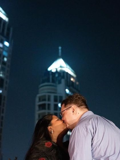 A romantic kiss against the backdrop of Mumbai's glittering skyscrapers at night, creating a glamorous and modern pre-wedding portrait.