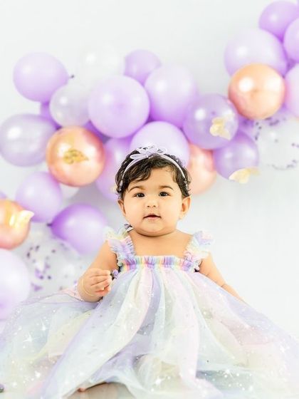 Dressed in a rainbow of pastel colors, this little princess sits patiently before her butterfly-themed cake smash.