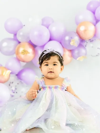 Dressed in a rainbow of pastel colors, this little princess sits patiently before her butterfly-themed cake smash.