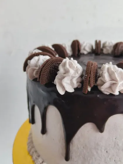 A detailed shot of the chocolate drip and piped cream swirls on the Oreo cake.