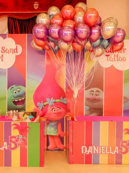 These activity stalls for a Trolls-themed party are decorated with characters from the movie and vibrant colors. We set up dedicated areas for bottle sand art and glitter tattoos.