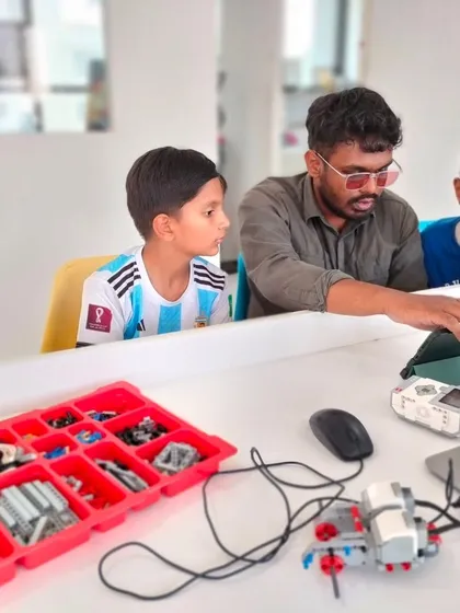 An instructor provides guidance to two students during our summer camp, helping them with their LEGO Spike Prime kit.