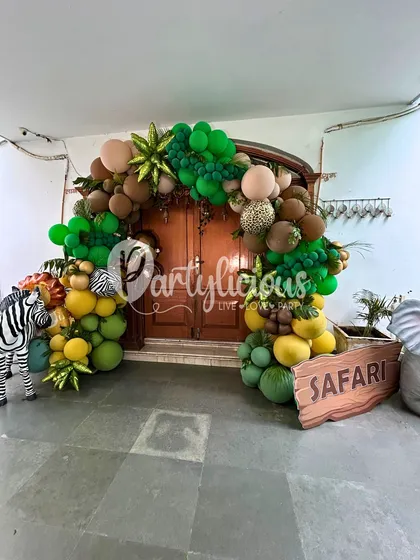 An inviting entrance to a safari party. We created this lush balloon arch over a doorway, complete with a zebra prop and a wooden 'Safari' sign to welcome the little adventurers.