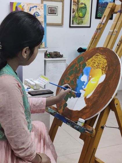 Multiple students are seen working on their own interpretations of Buddha paintings, showcasing a calm and focused studio environment.