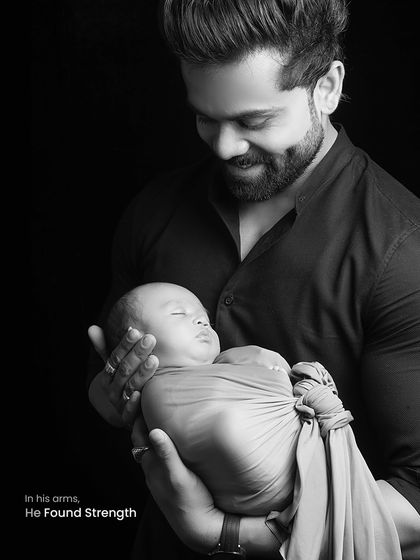 A father's strength and gentleness are on full display in this black and white portrait. He cradles his swaddled baby with a look of pure admiration and love.
