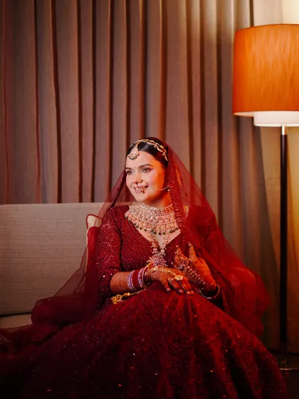 A serene bridal portrait. The bride is seated, bathed in the warm glow of a lamp, creating a calm and beautiful moment before the ceremony.
