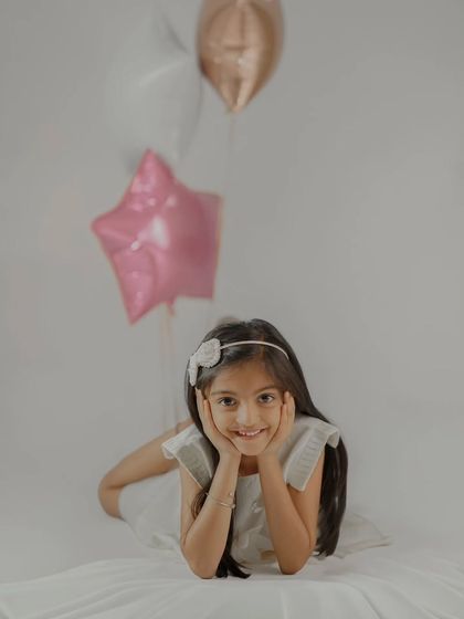A simple and sweet pose for a birthday photoshoot. The clean, minimalist background puts all the focus on the child's happy expression.