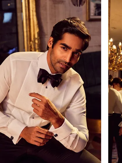A classic men's fashion portrait for a formal wear collection. The pose is relaxed yet confident, and the lighting creates a warm, inviting mood suitable for a luxury brand.