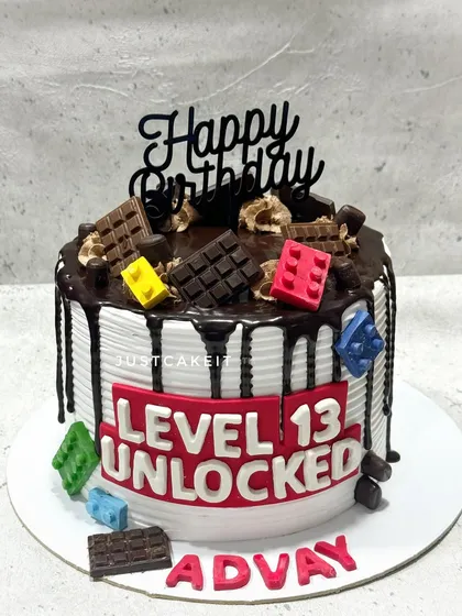 A fun "Level 13 Unlocked" cake perfect for a teenage gamer. This design combines a chocolate drip with edible Lego blocks and a bold gaming-themed message.