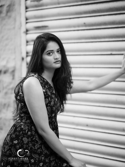 A moody and atmospheric portrait against a textured shutter door. The black and white tones enhance the gritty, urban feel of the location.