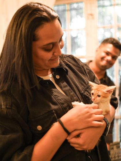 A participant shares a quiet moment with a tiny ginger kitten, both looking content.