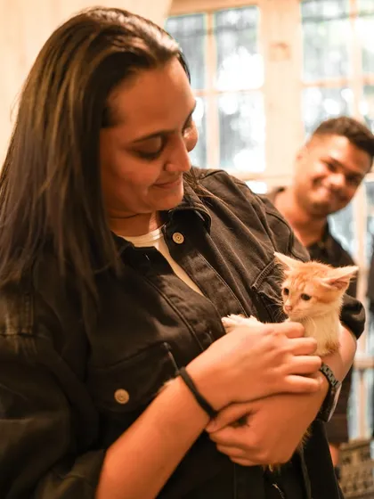 A participant shares a quiet moment with a tiny ginger kitten, both looking content.