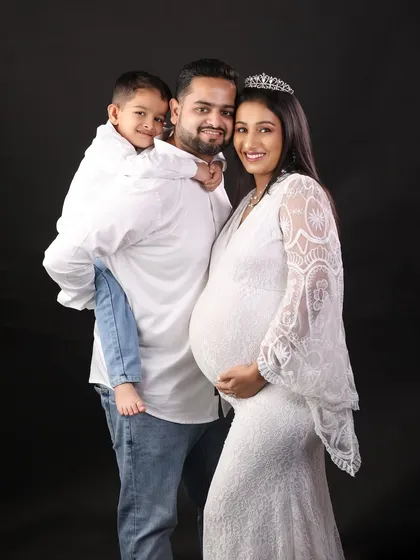 A happy family portrait, with dad giving his son a piggyback ride while standing next to the glowing mother-to-be.