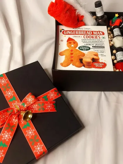 A close-up of the OPI Christmas PR box, featuring gingerbread man cookies and a curated selection of their nail polishes, all tied with a festive ribbon.