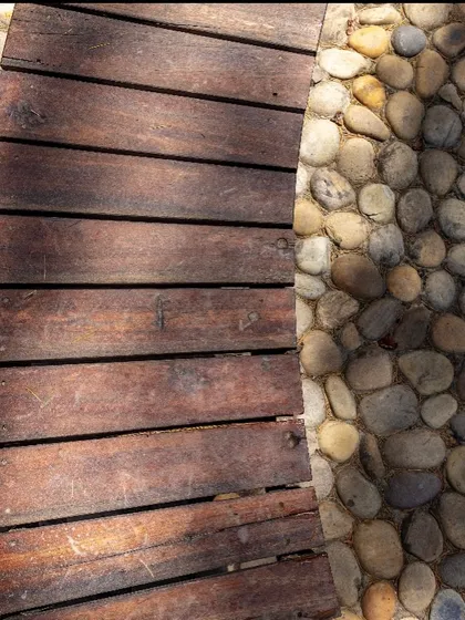 A detail shot of the material palette, combining smooth, upcycled wood with natural river stones for a tactile and contextually appropriate finish.