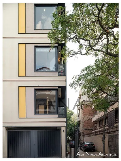 The front facade of the Yellow Line Apartment, showing the relationship between the large windows and the narrow balcony. Dark grey aluminum frames provide a strong definition to the openings.