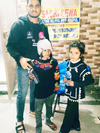 Two young girls receive warm hats and mufflers. Protecting the vulnerable is a key part of our winter charity efforts.