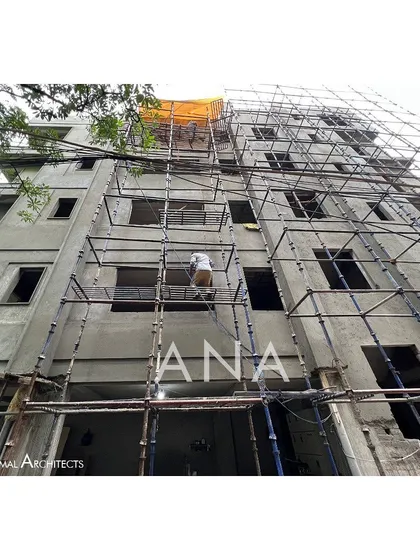 A low-angle view of the Yellow Line Apartment facade during construction, with workers applying plaster. This highlights the scale of the building and the labor involved in its creation.