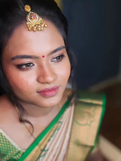 A close-up of a bride's engagement look, with soft makeup and a beautiful green saree.
