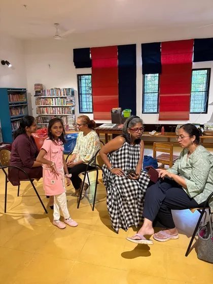 A small group, including a young girl, engaged in conversation during a community meetup. We cherish these moments of intergenerational connection.