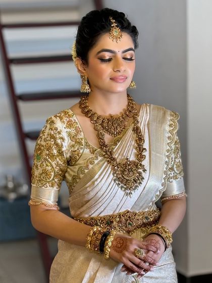 This bride's makeup features a subtle smoky eye and a nude lip, allowing her intricate temple jewelry and embroidered blouse to take center stage.