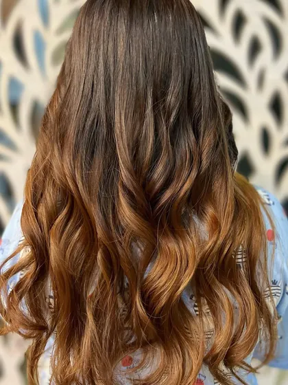 A beautiful copper and brown ombre, with the color transitioning smoothly from dark roots to lighter ends. The hair is styled in waves to enhance the color gradient.