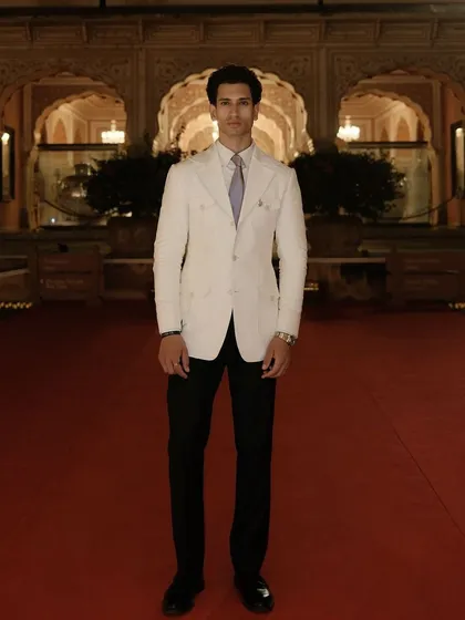 A powerful stance on the red carpet. The full-length view of the white linen suit shows its impeccable tailoring and elegant silhouette.