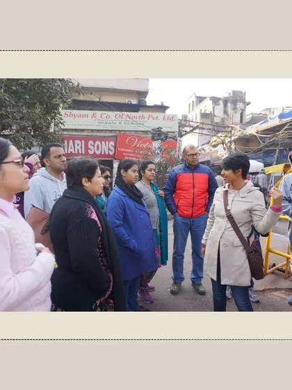 I am explaining the history of Chandni Chowk to a group, with the old market buildings in the background. We discuss how place names were often derived from local trades or notable figures.