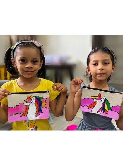 Two proud young artists showing off the unicorn pouches they painted themselves. In my workshops, kids get to create their own personalized accessories to take home and use.