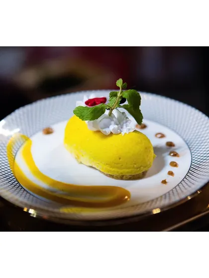 A luscious mango mousse cake, shaped elegantly and garnished with fresh mint. This dessert is a celebration of the king of fruits.