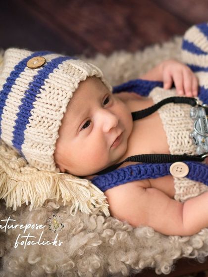 An awake newborn holding a miniature camera, a fun prop for a future photographer.