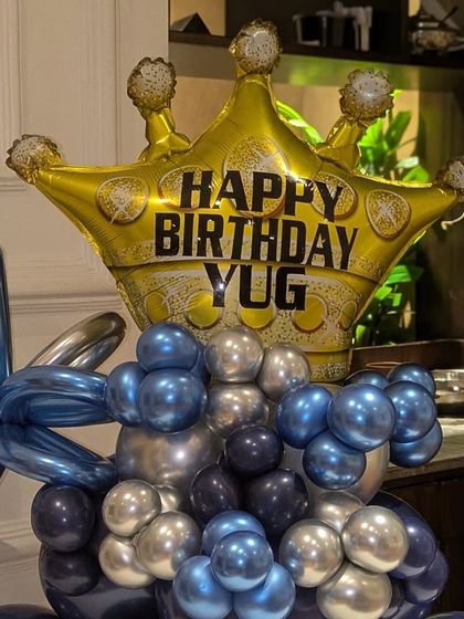 A close-up of the personalized "Happy Birthday YUG" crown foil balloon, the highlight of this unique arrangement.