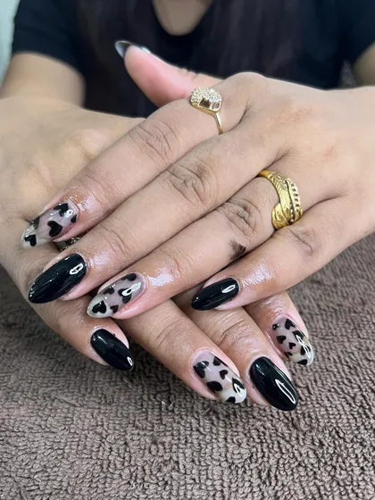 A trendy design with a mix of solid black nails and sheer nails with hand-painted black hearts.