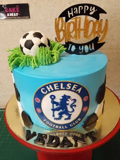 A Chelsea Football Club themed cake for a true fan. It features the club's logo, a fondant soccer ball, and buttercream grass.